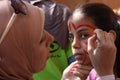 Female teacher painting little girls face in butterfly shape in playground