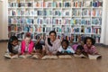 Female teacher and schoolkids reading a book while lying on floor of school library Royalty Free Stock Photo