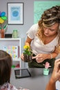 Female teacher showing pansy plant roots to her students in ecology classroom