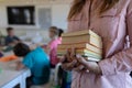 Female teacher standing in a classroom  holding a pile of books Royalty Free Stock Photo