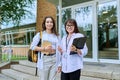 Female teacher and teenage girl student together, outdoor school building background. Royalty Free Stock Photo