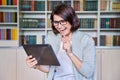 Female teacher using digital tablet for video conference, sitting in library office Royalty Free Stock Photo