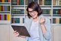Female teacher using digital tablet for video conference, sitting in library office Royalty Free Stock Photo