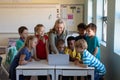 Female teacher using a laptop computer with group of schoolchildren