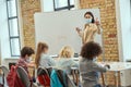 Female teacher wearing protective mask during coronavirus pandemic writing mathematic task on board for group of Royalty Free Stock Photo