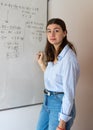 Young woman teacher explaining complex math equations on a whiteboard during an online class, providing education and e Royalty Free Stock Photo