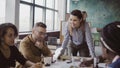 Female team leader standing near table and giving direction to young creative team. Brainstorming of multiethnic group. Royalty Free Stock Photo