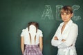 Female techer punishment her girl student over chalkboard Royalty Free Stock Photo