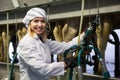 Female technician dairymaid operating machine milking in livestock barn