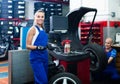 female technician standing with wheel balancing machinery at auto workshop Royalty Free Stock Photo