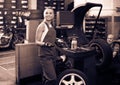 female technician standing with wheel balancing machinery at auto workshop Royalty Free Stock Photo