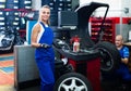 Female technician standing with wheel balancing machinery at auto workshop Royalty Free Stock Photo