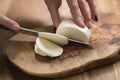 Female teen hand slicing mozzarella cheese with knife on wooden board Royalty Free Stock Photo