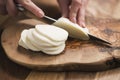 Female teen hand slicing mozzarella cheese with knife on wooden board Royalty Free Stock Photo