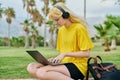 Female teenage student in headphones sitting in park with laptop. Royalty Free Stock Photo