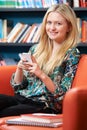 Female Teenage Student Using Mobile Phone In Library Royalty Free Stock Photo