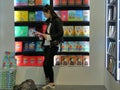 Female teenager choosing a book in colorful bookstore
