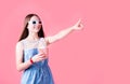 Female teenager girl wearing 3D glasses eating popcorn and pointing her finger isolated on pink background Royalty Free Stock Photo