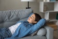 Female teenager lying on sofa with closed eyes enjoying comfort