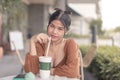 A female teenager poses for the camera with a smized eyes while holding the straw of her frappe