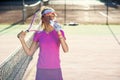Female tennis player in pink uniform drinking water from plastic bottle after tennis training on the outdoor court at Royalty Free Stock Photo