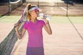 Female tennis player in pink uniform drinking water from plastic bottle after tennis training on the outdoor court at Royalty Free Stock Photo