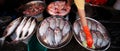 Female Thai vendor with orange latex gloves and sponge cleaning freshwater fish in stainless steel try at the local wet market,