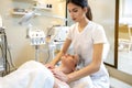 Female therapist massager administering decollete massage to young woman relaxing on table in spa salon