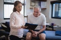 Female therapist showing clipboard to senior male patient sitting on bed Royalty Free Stock Photo