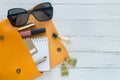 Fashion concept. Female things, cosmetic products, sunglass, notebook and orange handbag on wooden background with copyspace. Flat Royalty Free Stock Photo