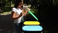 Female throwing out in the recycling bin disposable cup. Woman separate plactic lid with cardboard cup and thow into