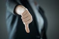 Female thumb down close-up on the background of suit in blur. Business concept