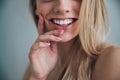 Female with a toothy smile touching her cheek with one hand Royalty Free Stock Photo