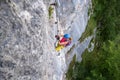 Female tourist, in colorful sport clothes, climbs a difficult vertical section on a via ferrata route above Hallstatt, Austria