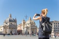 Female tourist with a fashinable vintage hipster backpack taking photo of Piazza del Popolo in Rome, Italy by her mobile Royalty Free Stock Photo