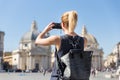 Female tourist with a fashinable vintage hipster backpack taking photo of Piazza del Popolo in Rome, Italy by her mobile Royalty Free Stock Photo