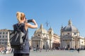 Female tourist with a fashinable vintage hipster backpack taking photo of Piazza del Popolo in Rome, Italy by her mobile Royalty Free Stock Photo