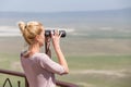 Female tourist looking through binoculars on African safari in Ngorongoro crater consrvation area, Tanzania, Afrika. Royalty Free Stock Photo