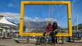 Female and Male tourist with face masks on sitting on big yellow frame which frames Table Mountain.