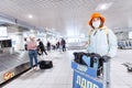 Female tourist with medical protective antiviral mask with cargo cart at Domodedovo airport