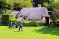 Female tourist photographer taking a photograph of a thatched roof cottage Royalty Free Stock Photo