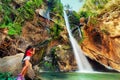 Female tourist photographing a waterfall in forest Royalty Free Stock Photo