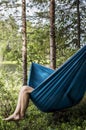 Female tourist is resting in a hammock in the forest, on a blurred background of a lake and pine trees. Royalty Free Stock Photo