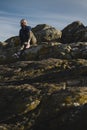 A female tourist sits on the coastal ocean cliffs.