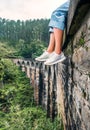 Female tourist sits on the Demodara nine arches bridge in Ella,