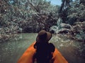 Female tourist sits in a kayak in a small canal.