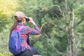 A female tourist sits on a rock using a binoculars to see the be