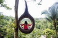 A female tourist is sitting on a large bird nest on a tree at Bali island Royalty Free Stock Photo