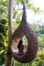 A female tourist is sitting on a large bird nest on a tree at Bali island Royalty Free Stock Photo