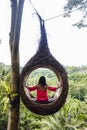 A female tourist is sitting on a large bird nest on a tree at Bali island Royalty Free Stock Photo